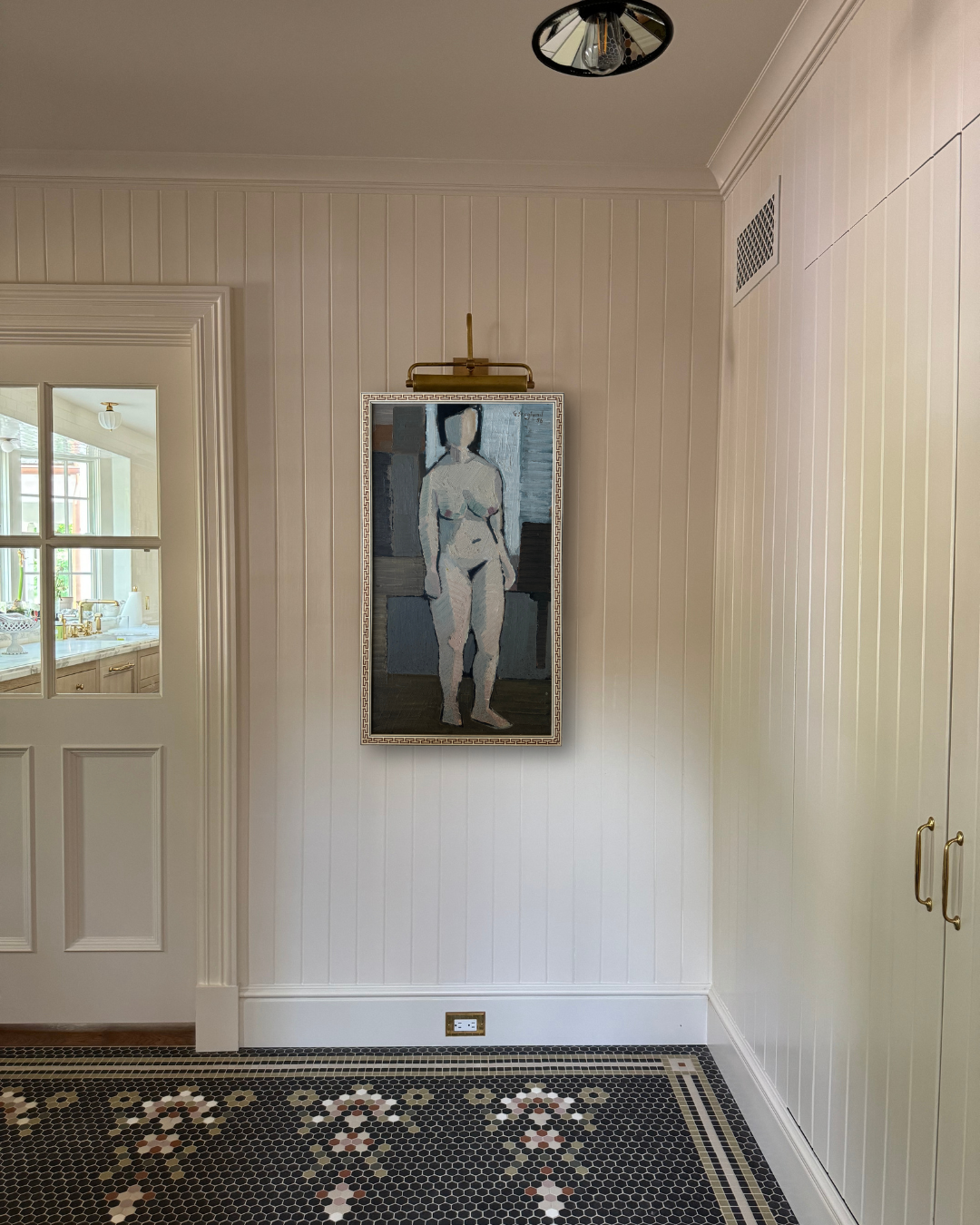 Framed artwork of a nude figure on a wall in a room with a tiled floor.