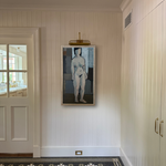 Framed artwork of a nude figure on a wall in a room with a tiled floor.